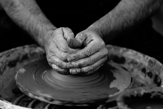 black and white image hands moulding clay on potters wheel 